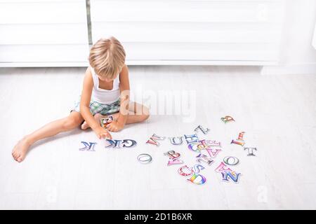 Beautiful little boy learning letters on the floor at home. Stock Photo