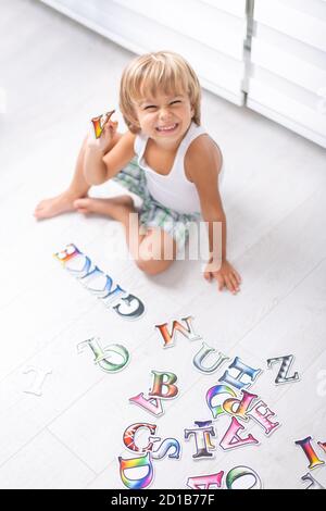 Beautiful little boy learning letters on the floor at home. Stock Photo