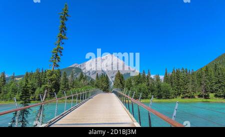 Banff city in Alberta, Canada. The view on the bridge over turquoise Bow river. Pine tree woods / forest and Mount Rundle in the background. Stock Photo