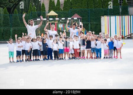 Group of children with coaches posing and waving before the lesson start. Sport school Stock Photo