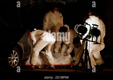 Forensic workers cover the body of man, with part of his body covered with tape, found in the trunk of a car in the suburb of San Nicolas in the northern city of Monterrey November 21, 2007. About 102 people have been killed, including 29 policemen, since the beginning of the year in a wave of violence in the business city, according to local media. Picture taken November 21, 2007. REUTERS/Tomas Bravo (MEXICO)