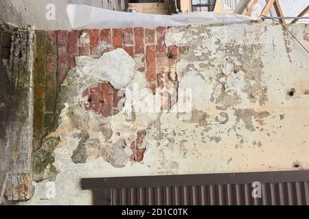 destroyed brick wall with fallen off plaster. Stock Photo