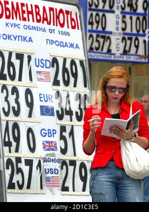 A woman reads as she stands in front of a currency exchange rate board in Moscow June 30, 2006. The many, often derogatory, names Russians have for their roubles stem from the Soviet Union, where the national currency was officially more valuable than the dollar but worthless outside its borders. From Saturday, officials hope, that age will be past. The last restrictions on the rouble will be scrapped, and it will become convertible -- a currency like the dollar or the yen.   REUTERS/Ivan Chernichkin (RUSSIA)