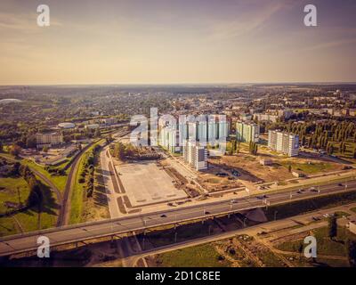 Part of the city with new buildings, bridge, construction site on a summer day at sunset, view from the drone. Stock Photo
