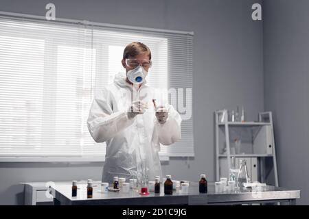 A scientist with gloved hands burning a piece of paper in his lab. Stock Photo