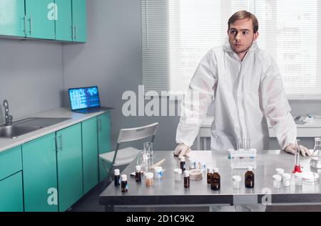 Modern interior of a laboratoratory in a research center. A lab worker in protective clothing standing at the table. Stock Photo