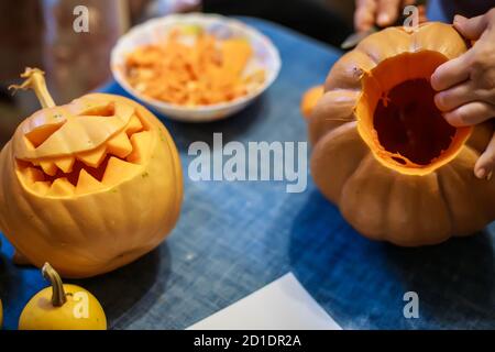 process hands cutting with knife character face on pumpkin object preparation to halloween holiday Stock Photo