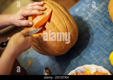 halloween, decoration and holidays concept - close up of woman with knife carving pumpkin or jack-o-lantern at home Stock Photo
