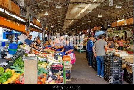 Local French citizens enjoy the weekly covered produce market inside the walled old town of Antibes along the French Riviera and Cote d'Azur. Stock Photo