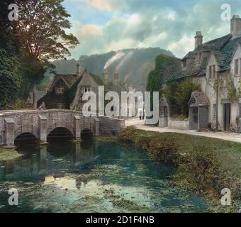 Colorized view of a stone bridge over the River Bybrook which leads to the village of Castle Combe, Wiltshire, England, 1914. (Photo by Burton Holmes) Stock Photo