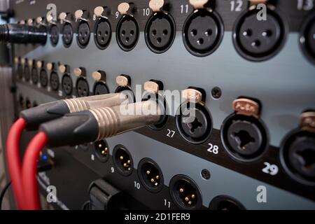 Jack-type audio connectors inserted into the line inputs of a mixing desk with more jack and xlr inputs and outputs in a professional recording studio Stock Photo