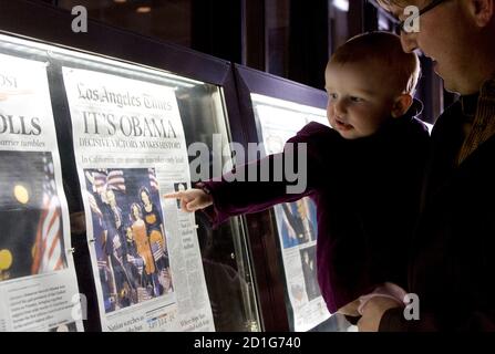 Nora Sherman, 18 months old, and her father Paul Sherman of Washington view the front pages of Wednesday's newspapers from around the world on display outside the Newseum in Washington November 5, 2008. Americans woke with joy, cautious optimism and frank worry on Wednesday after the historic win by Democrat Barack Obama, who went from long shot to president-elect on the promise of change.   REUTERS/Molly Riley   (UNITED STATES)