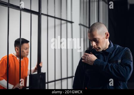 A stern, bald prison warden makes the rounds of the cells and transmits information over the radio to the head of the prison guard Stock Photo