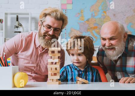 Pupil with father and grandfather enjoying together at home. Playing Jenga. Stock Photo