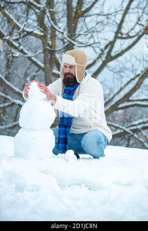 Fashion portrait of handsome man indoors with Snowman. Hipster posing with snowman on white winter background. Christmas holidays and winter new year. Stock Photo