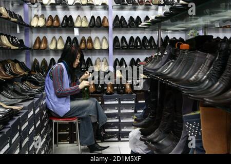 A shopkeeper waits for customers at a shoe store in Beijing August 