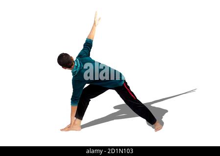 Full-length shot of male teenager practicing Revolved Yoga Pose or Revolved Triangle Yoga Pose or Parivrtta Trikonasana isolated on white background. Stock Photo