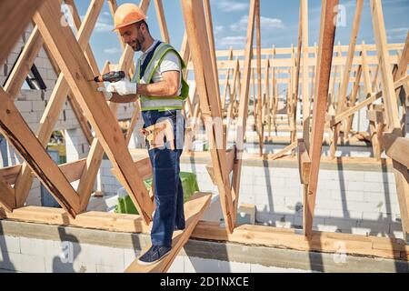 Cheerful male person working on building of his house Stock Photo