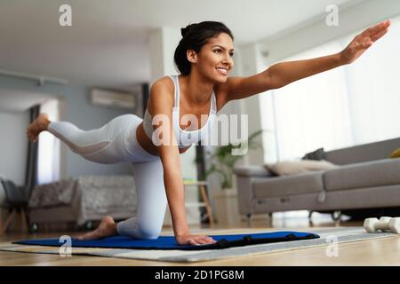 Beautiful fit woman exercise fitness at home instead of going to the gym. Stock Photo