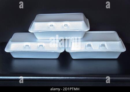 Front view of Styrofoam takeaway boxes, white foam boxes, rectangular shaped clamshell style container with an attached lid, on black background Stock Photo