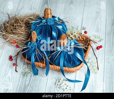 Beautiful blue pumpkins made of velvet fabric are decorated with various elements and ribbons in  small wicker basket. Home decor for  Halloween Stock Photo