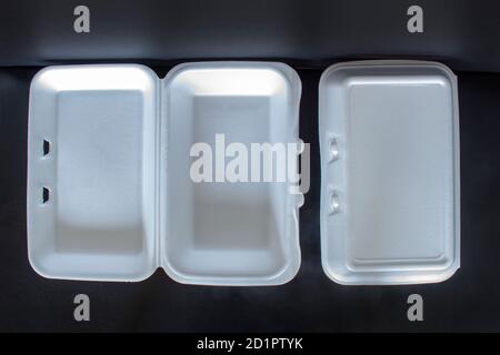 Top view of Styrofoam takeaway boxes, white foam boxes, rectangular shaped clamshell style container with an attached lid, on black background Stock Photo