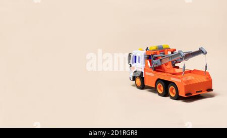 Toy orange tow truck on beige background banner with space for text. Children's car for loading and transporting cars Stock Photo