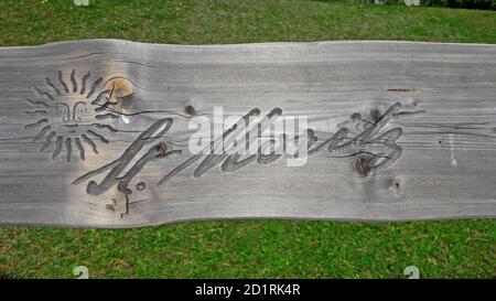 St. Moritz, Graubünden, Switzerland - 30th September 2020 : St. Moritz sign engraved on a wooden bench with green grass in the background. St. Moritz Stock Photo
