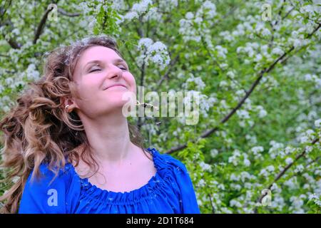 Woman shakes her hair shaking off white dandelion seeds Stock Photo