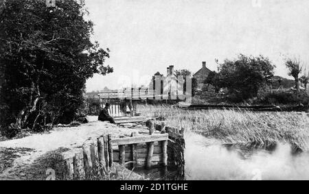 ST JOHN'S LOCK, Lechlade, Gloucestershire. The weir and lock keeper's house at St John's Lock on the River Thames. A man sits on the riverbank and contemplates the reeds. (Published in Taunt's 'New Map of the River Thames', 5th edition, 1886-7). Photographed between 1860 and 1887 by Henry Taunt. Stock Photo