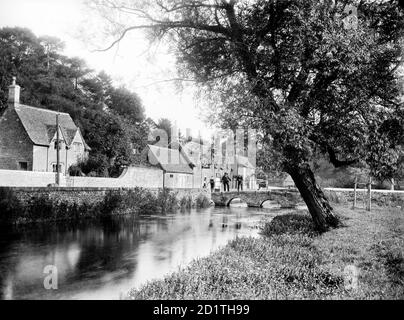 BIBURY, Gloucestershire. Looking along the river towards the stone bridge beside Arlington Row. The Cotswold village of Bibury was described as the most beautiful village in England by William Morris. Photographed in 1906 by Henry Taunt. Stock Photo
