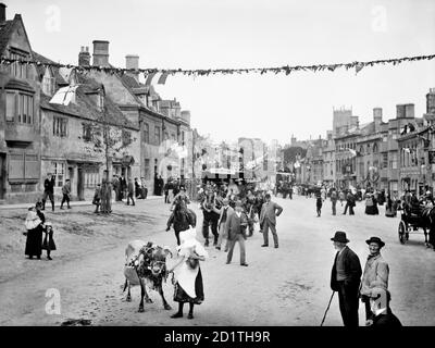 CHIPPING CAMPDEN, Gloucestershire. A milkmaid with a calf followed by a cart bedecked in flowers and flags form part of the procession through the Cotswold town during the Floral Festival. The Flower Festival was part of Chipping Campden's long established tradition of Whitsun festivities that continued up until the outbreak of the First World War. Photographed by Henry Taunt in 1896. Stock Photo