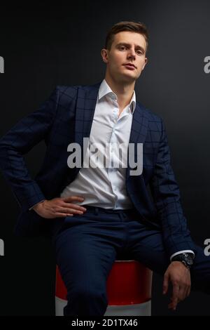 portrait of sublime rich well-off man in suit isolated on black background. male in classic wear has own business, sits on oil barrel. success concept Stock Photo