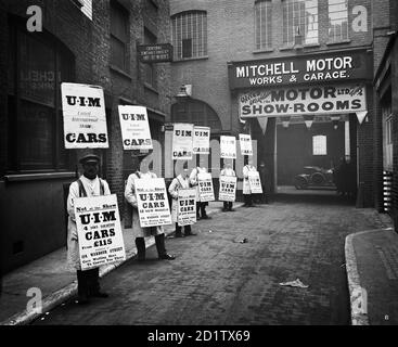 WARDOUR STREET, London. A line of men standing outside Mitchell Motors Company (114 Wardour Street), wearing sandwich boards advertising United International Motors Ltd. At the time the photograph was taken the garage was being used as a temporary motor showroom. Photographed by Bedford Lemere & Co in October-November 1910. Stock Photo