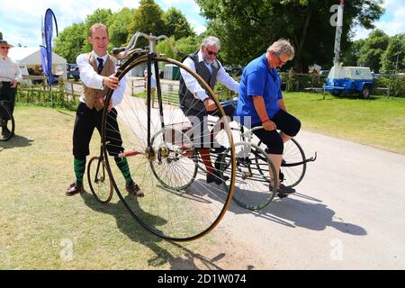 An elderly couple riding a vintage quadricycle at the Traditional Boat Festival in Henley-on-Thames, Oxfordshire, UK Stock Photo