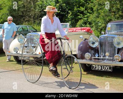 A woman riding a vintage tricycle at the Traditional Boat Festival in Henley-on-Thames, Oxfordshire, UK Stock Photo