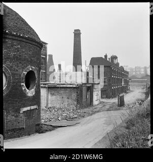 Josiah Wedgwood's Etruria Pottery Works during demolition, viewed from towpath of the Trent and Mersey Canal with the Round House in the foreground, Etruria Road, Etruria, Stoke-on-Trent, Staffordshire, UK.   Josiah Wedgwood opened his Etruria Works beside the Trent and Mersey Canal in 1769. A new factory was constructed at Barlaston in 1938 and production was gradually shifted away from Etruria. The Round House (built circa 1769), said to have been used for grinding raw materials, as a counting house, and as a stable, is now the only surviving structure. Stock Photo