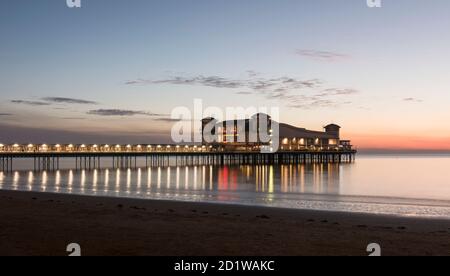 Grand Pier, Marine Parade, Weston-Super-Mare, North Somerset. General view of the pier, illuminated at dusk, from the north-east, at mid-tide. Stock Photo