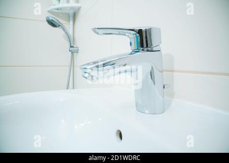 chromed metal faucet for hot and cold water  in a modern bathroom Stock Photo