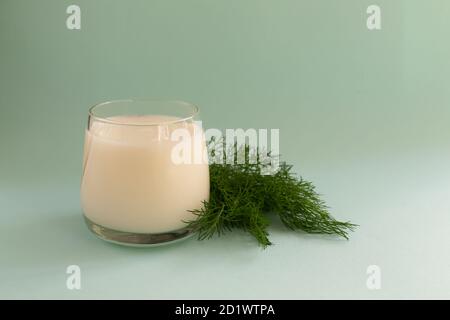 Ayran in a glass glass with a sprig of dill on a blue background. Fermented product concept. Copy space. Stock Photo