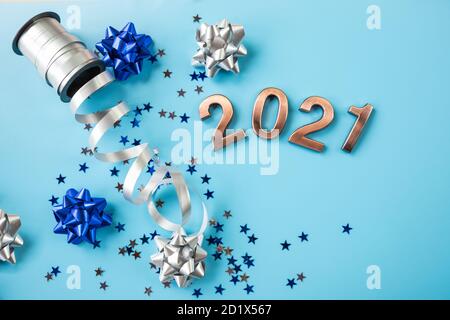 creative pattern with shiny bow from bright ribbon on blue background. Trendy silver,blue ribbon. Stylish metallic bows, Numbers of New year 2021 Stock Photo