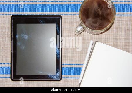 notebook with white pen, tablet PC and coffee on grey wicker background. Stock Photo
