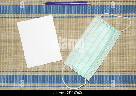 Notebook with eco pen and blue medical mask lie on background. Coronavirus epidemic concept. Stock Photo