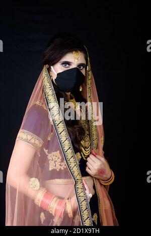 Bride wearing white Indian traditional cloth with face mask during wedding celebration in India Stock Photo