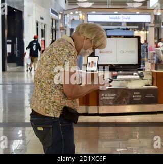 FRESNO, UNITED STATES - Sep 01, 2020: A photo of a Senior Citizen using her cell phone wearing a face Mask in the Mall during COVID 19 Stock Photo