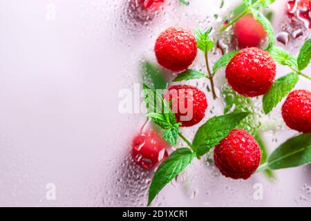 raspberries and mint with drops of water on a light background with copyspace closeup. Concept of food levitation. Stock Photo