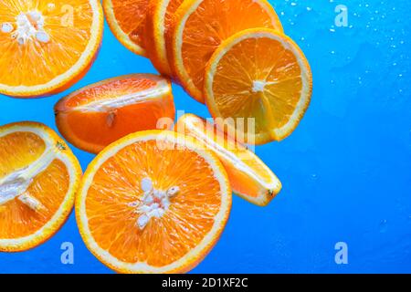 Orange slices on a blue background with water drops. The concept of proper nutrition. Stock Photo
