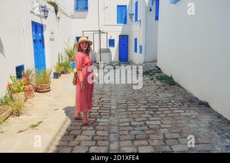 Girl stands in the courtyard with blue windows and doors with Arabic ornaments. Texture of Islamic symbols in Sidi Bou said, Tunisia, Africa Stock Photo