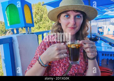 A girl drinks almond jasmine ea in an Arab cafe with blue umbrellas, Sidi Bou Said, Tunisia Stock Photo