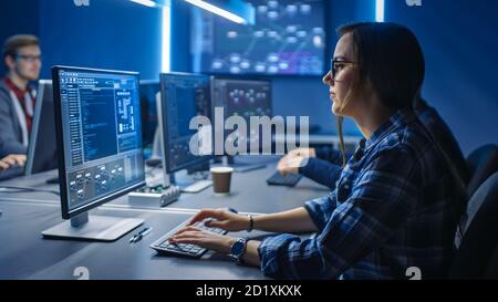 Smart Young Female IT Programer Working on Desktop Green Mock-up Screen Computer in Data Center System Control Room. Team of Young Professionals Stock Photo